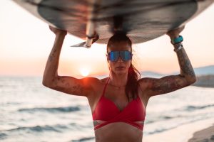 Strong girl on the beach with stand-up board during summer